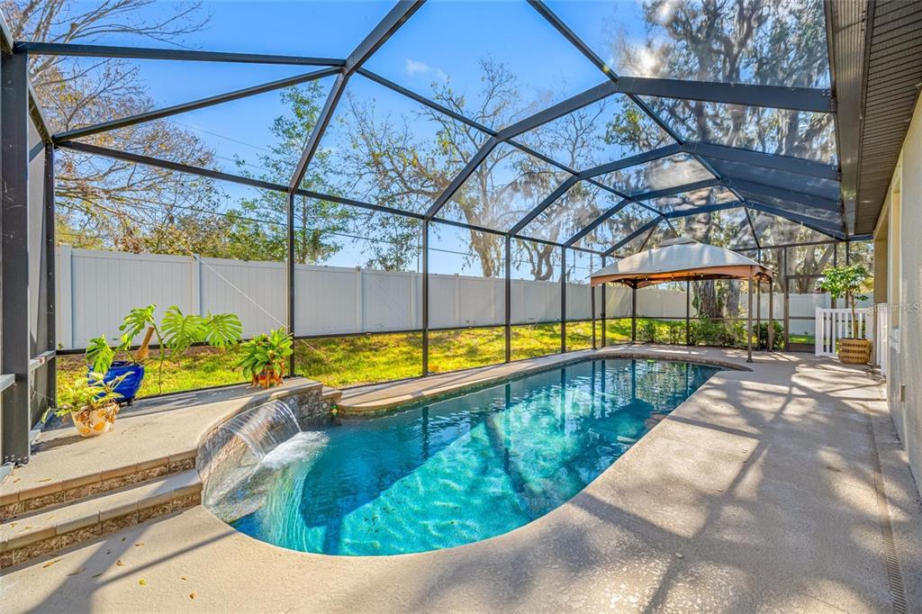 A screened-in swimming pool with a waterfall feature and a gazebo in a backyard — 11652 PALMETTO PINE STREET, RIVERVIEW, FL