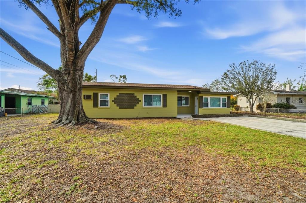A single-story house with yellow siding and a large tree in the front yard — 3022 HICKORY STREET NW, WINTER HAVEN, FL
