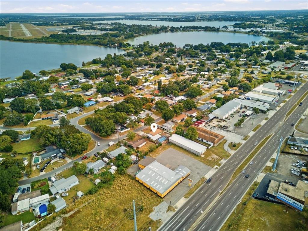 An aerial view shows a residential property with a pool near a lake and highway — 3022 HICKORY STREET NW, WINTER HAVEN, FL