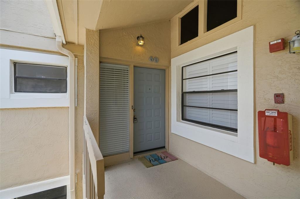 An exterior view of a building entrance with a light blue door and fire alarm — 60 ST ANDREWS PLACE UNIT 60, OLDSMAR, FL