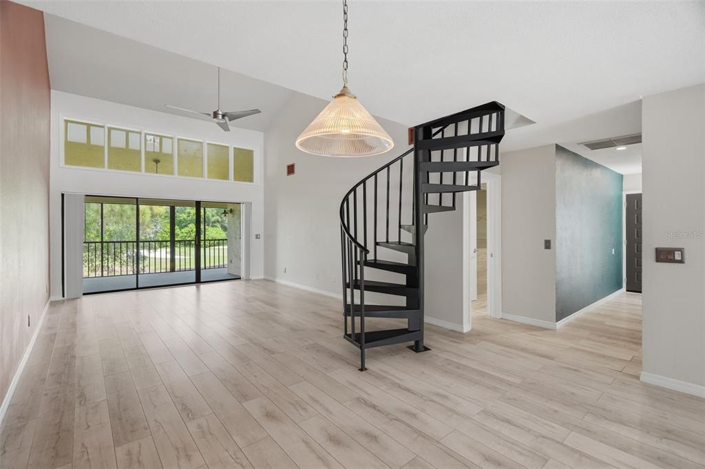 A living room features light wood flooring, a spiral staircase, and a large sliding glass door — 60 ST ANDREWS PLACE UNIT 60, OLDSMAR, FL