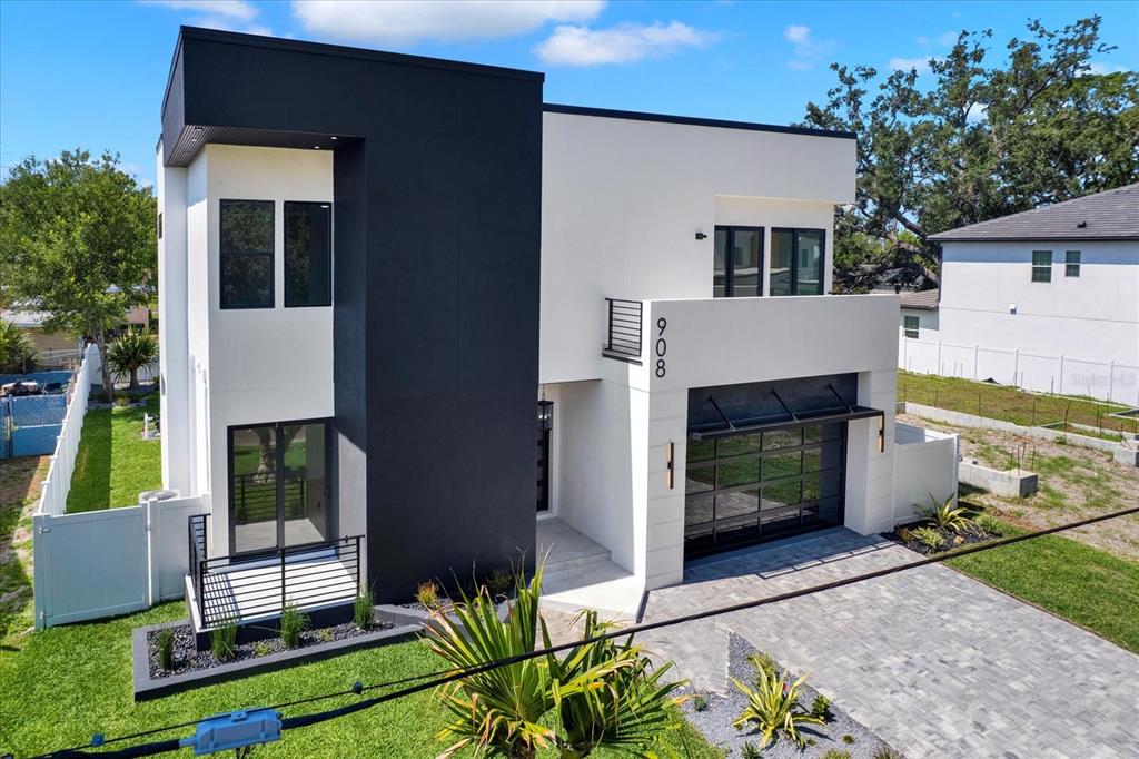 A modern two-story house features a black and white exterior with a glass garage door — 908 W FRIBLEY STREET, TAMPA, FL