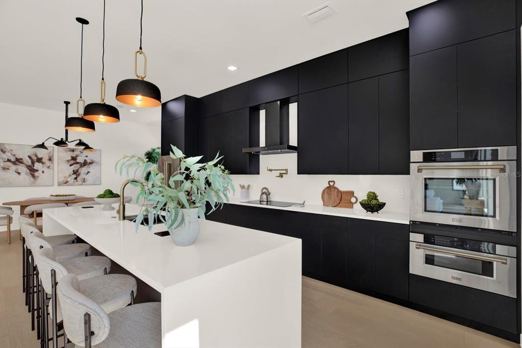 A modern open-concept living room and kitchen featuring light wood floors and a large sectional — 908 W FRIBLEY STREET, TAMPA, FL
