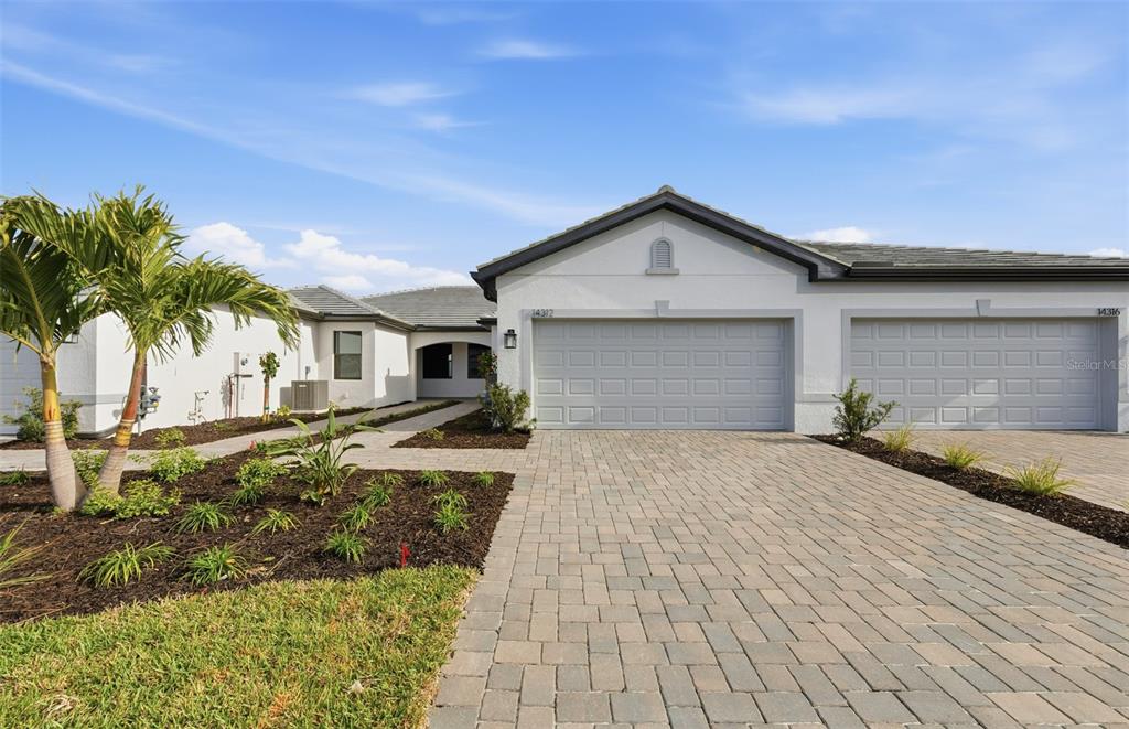 A single-story house with a paved driveway, two garage doors, and a landscaped front yard — 14864 MISTY POND LOOP, NOKOMIS, FL