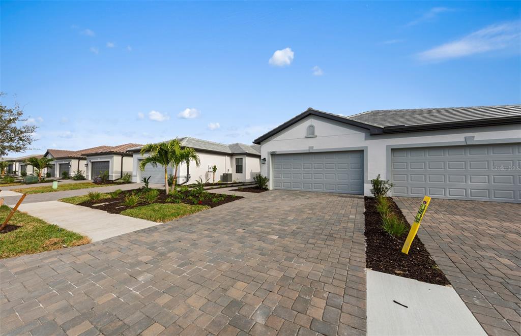 A view of the exterior of a suburban house with a paved driveway and garage — 14864 MISTY POND LOOP, NOKOMIS, FL