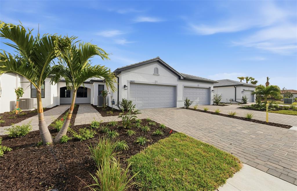 A single-story house with a paved driveway, two-car garage, and palm trees in the front yard — 14864 MISTY POND LOOP, NOKOMIS, FL