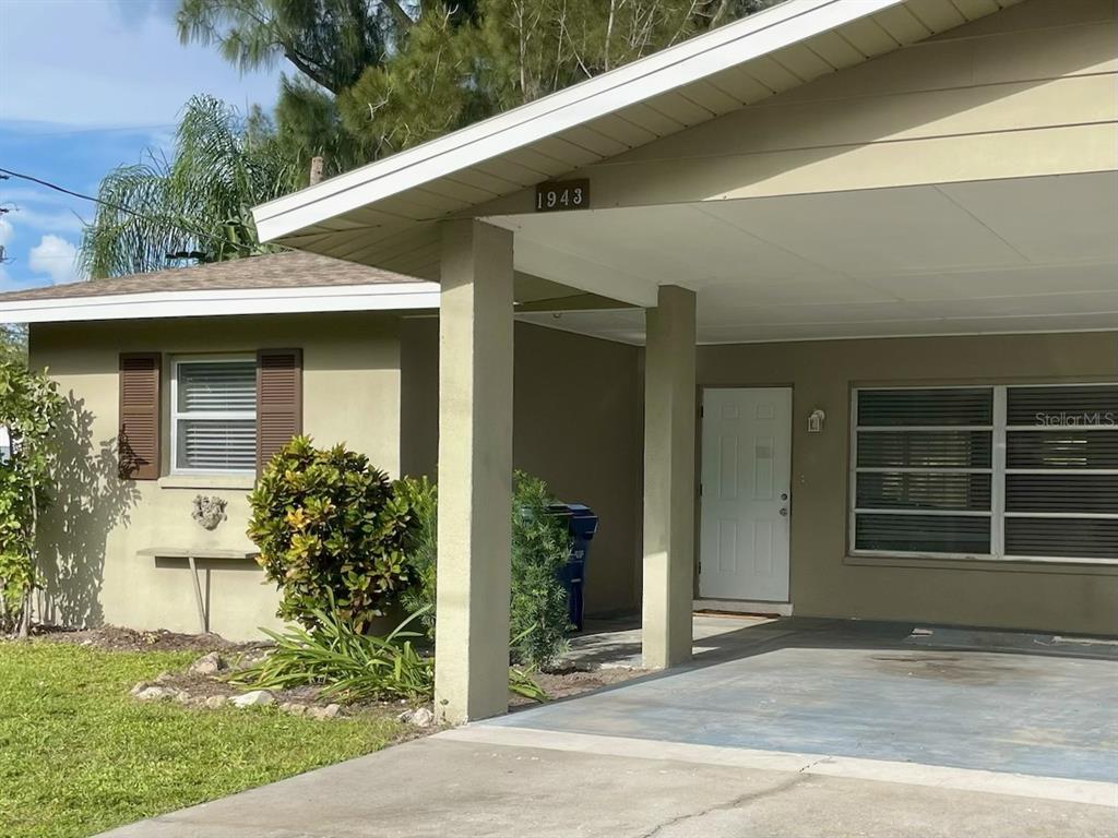 A single-story house with a tan exterior, a carport, and a white front door — 1941-1943 FORKED CREEK DR, ENGLEWOOD, FL