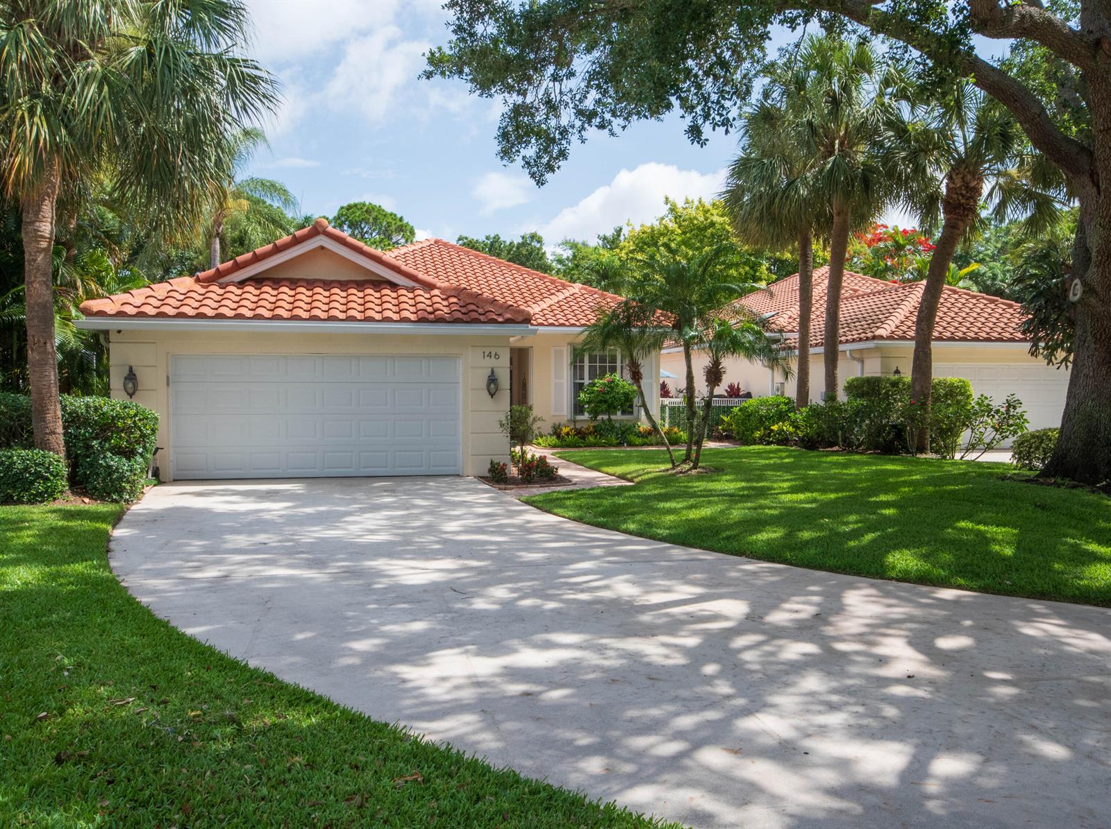 A single-story house with a tile roof, white garage door, and palm trees in front — 146 Lost Bridge Drive, Palm Beach Gardens FL 33410, PALM BEACH GARDENS, FL