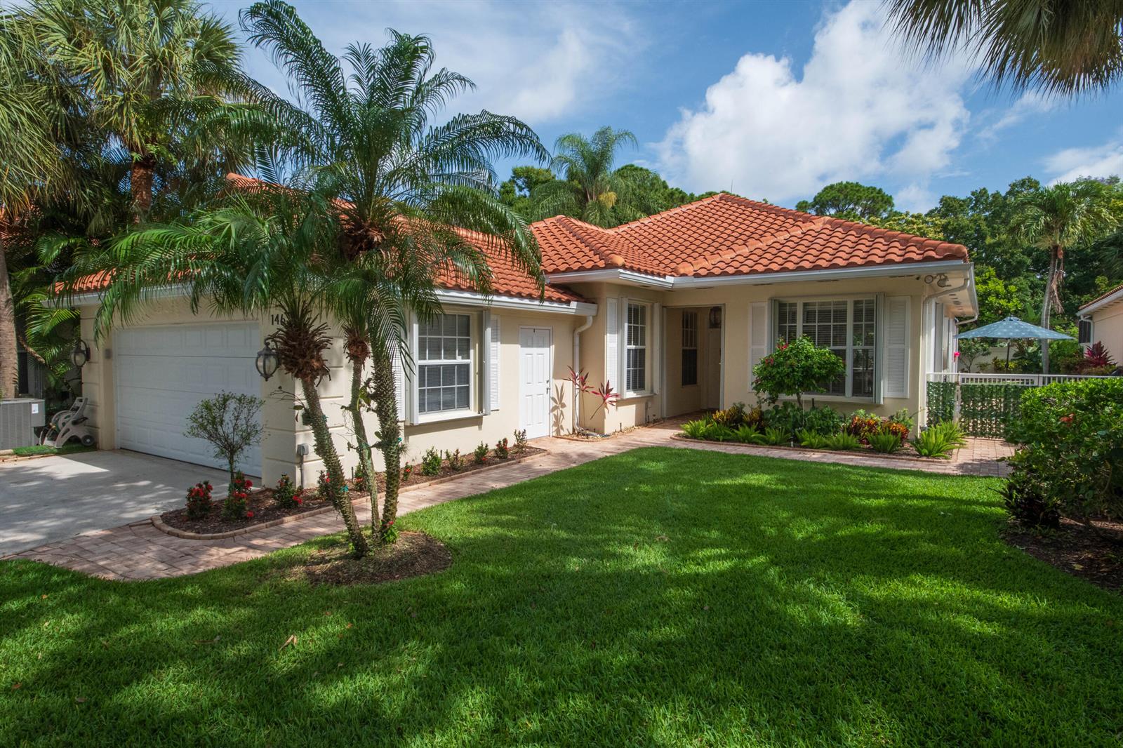 A single-story house with a terracotta tile roof, a two-car garage, and a front lawn — 146 Lost Bridge Drive, Palm Beach Gardens FL 33410, PALM BEACH GARDENS, FL