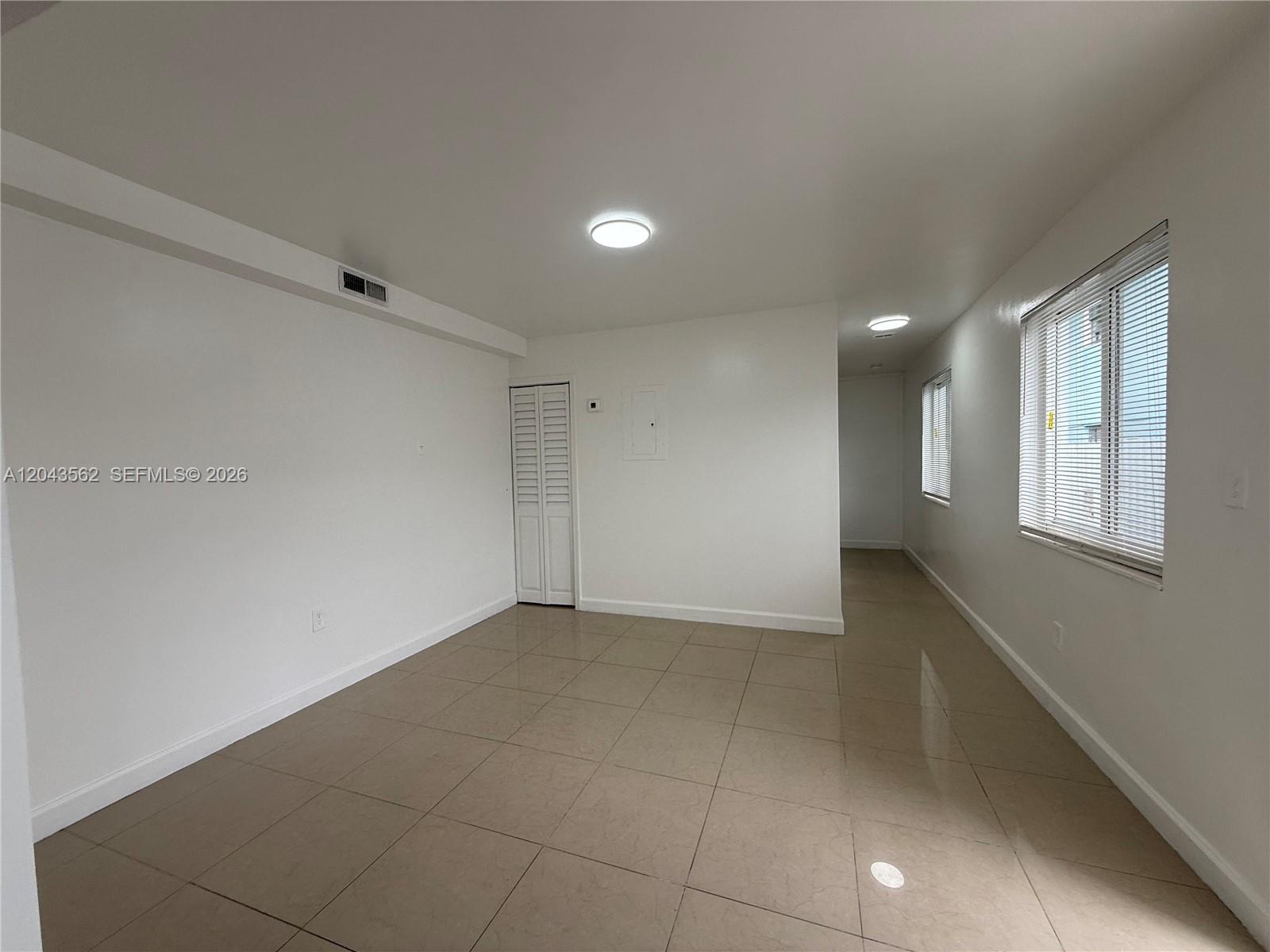 An empty room features white walls, beige tile flooring, and two windows with blinds — 1122 NW 32nd Ct, Miami FL 33125, MIAMI, FL