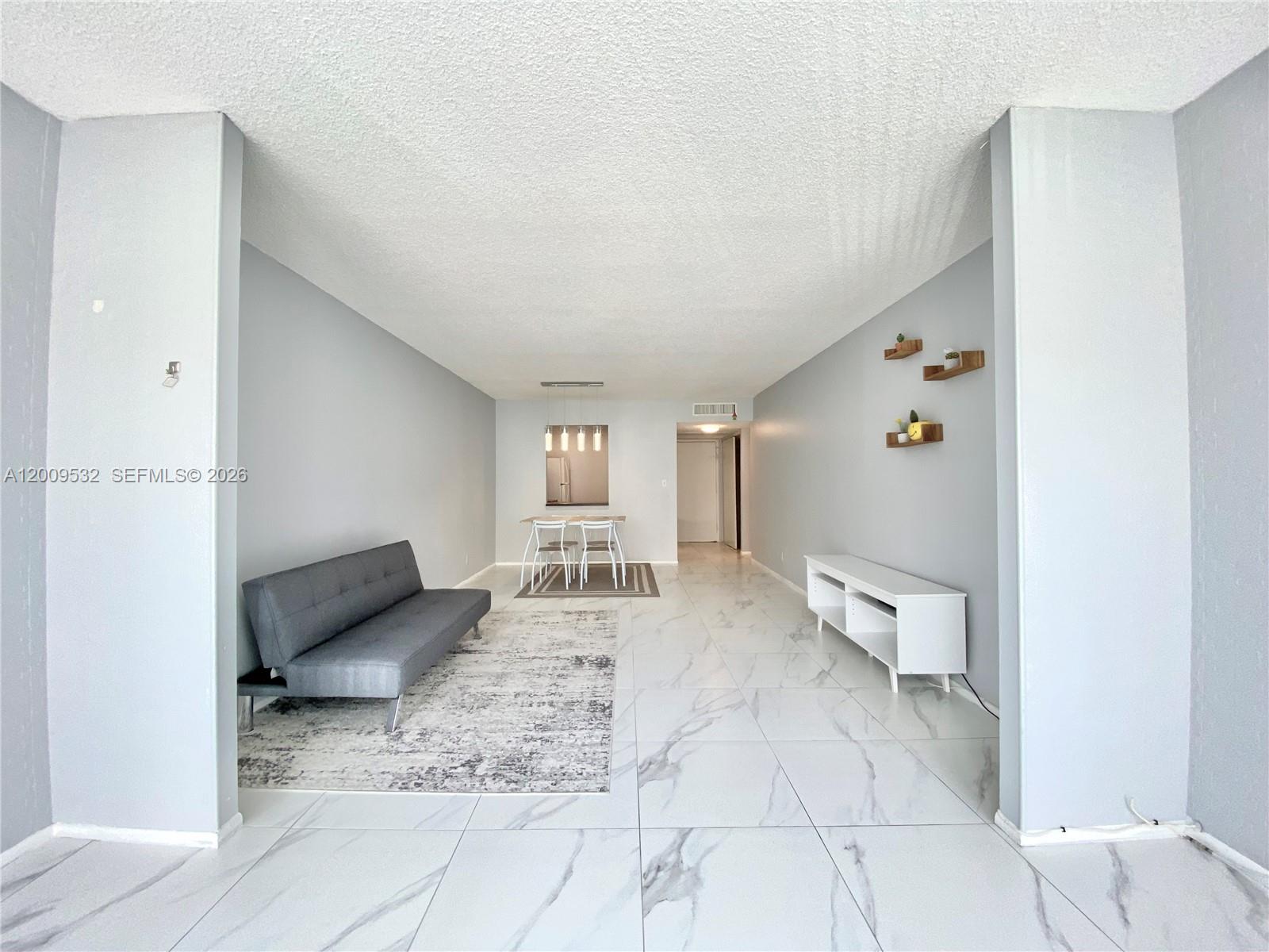 A living and dining area features light gray walls, white marble-look tile floors, and modern furniture — 601 Three Islands Blvd # 314, Hallandale Beach FL 33009, HALLANDALE BEACH, FL