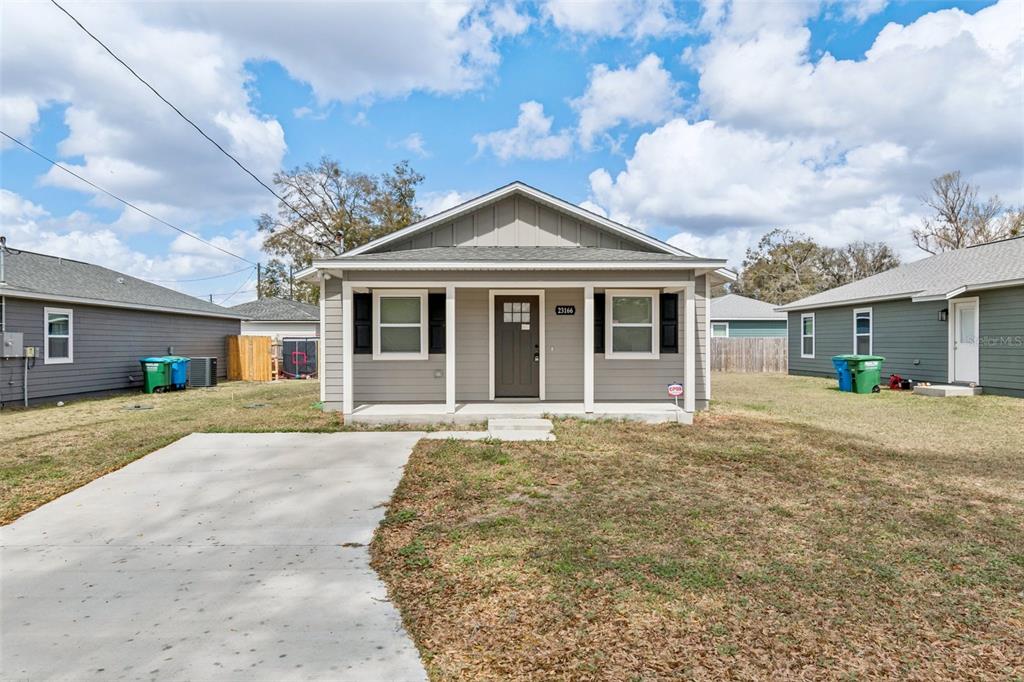 A single-story gray house with a covered front porch and a concrete driveway — 23166 NW 180TH AVENUE, HIGH SPRINGS, FL