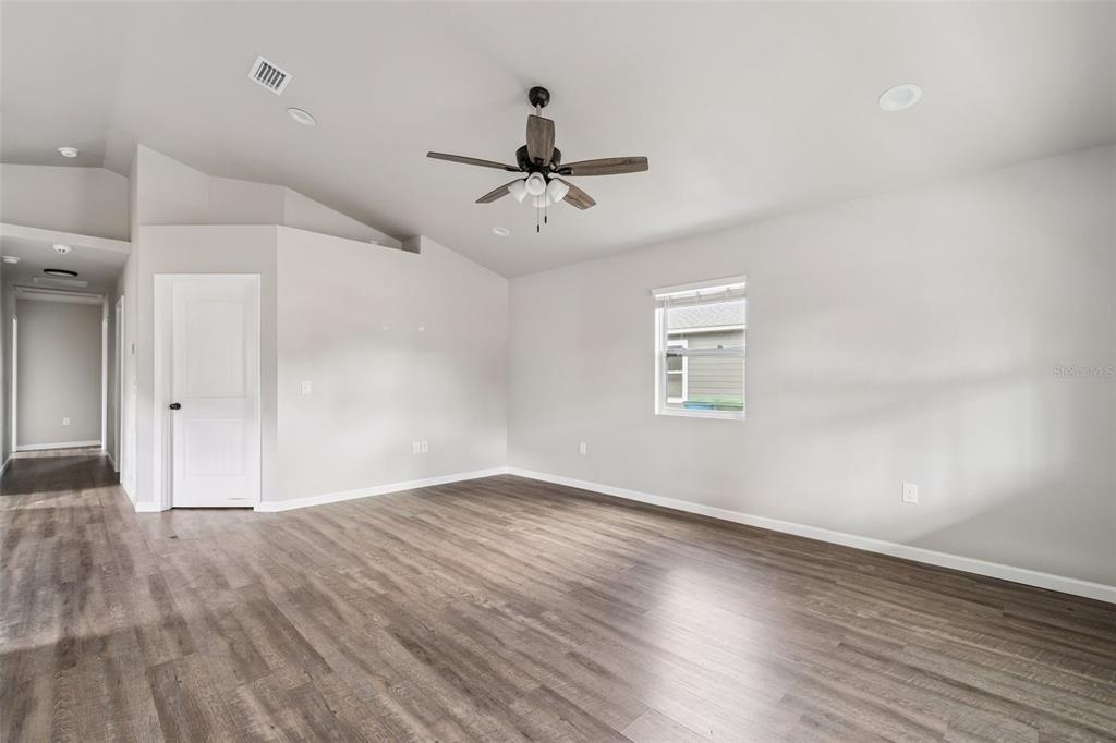 An empty living room features light gray walls, wood-look flooring, and a ceiling fan — 23166 NW 180TH AVENUE, HIGH SPRINGS, FL