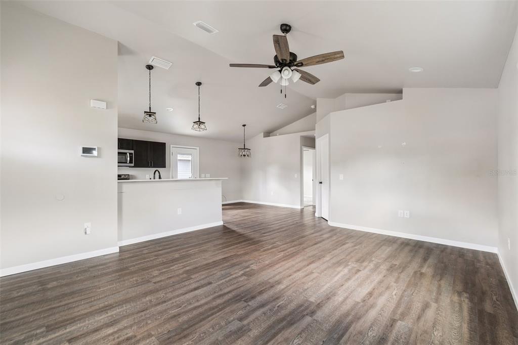 An open-concept living area features wood-look flooring, a ceiling fan, and a kitchen breakfast bar — 23166 NW 180TH AVENUE, HIGH SPRINGS, FL