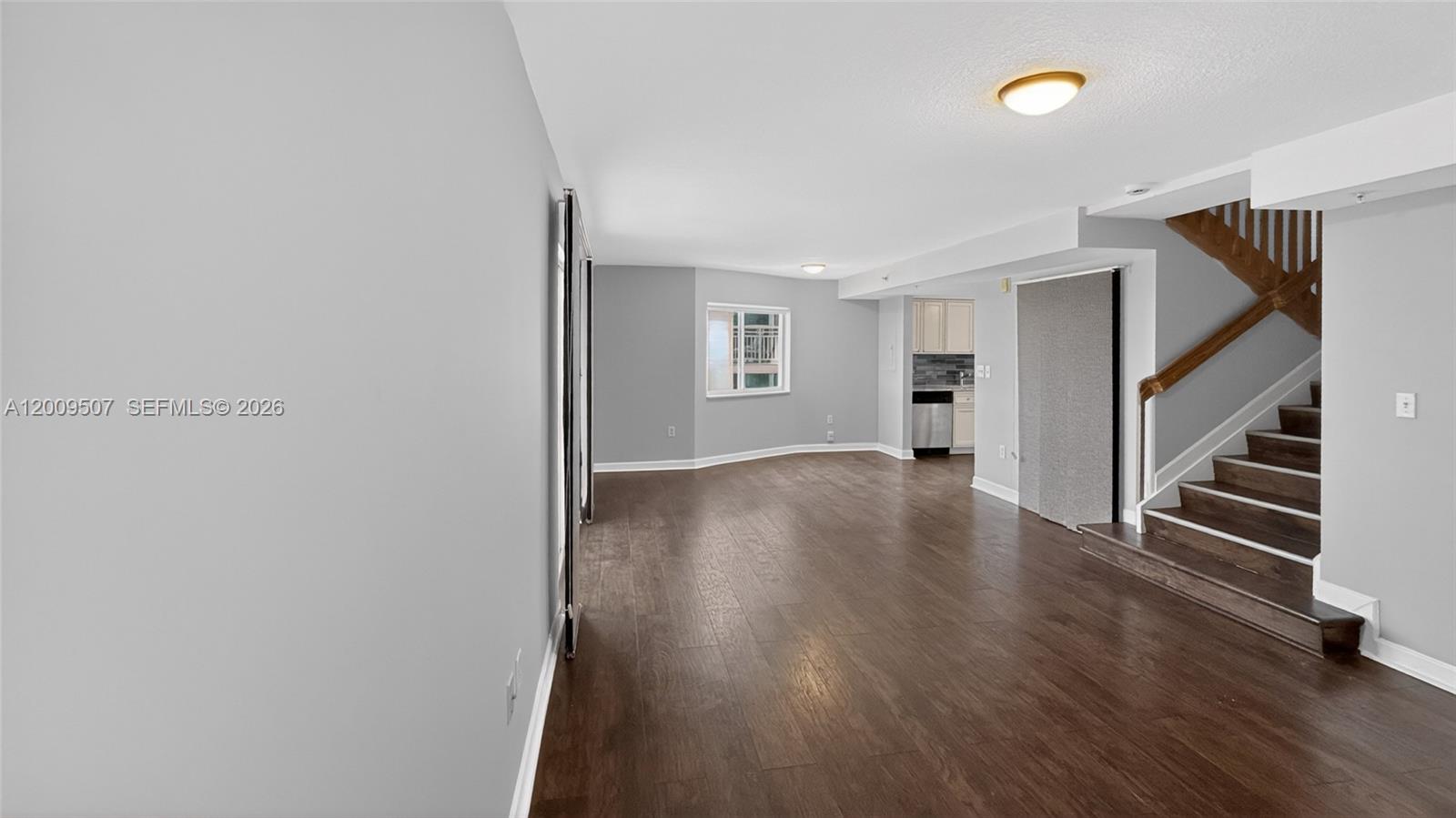 An empty living room features dark wood flooring, gray walls, and a wooden staircase — 280 SW 20th Rd # 904, Miami FL 33129, MIAMI, FL