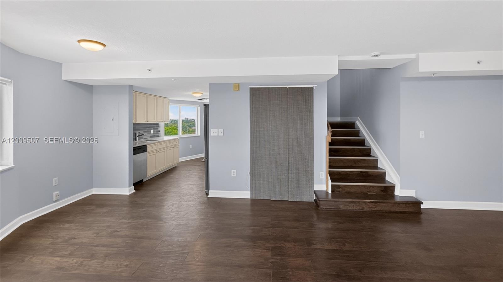 An open living area features dark wood floors, a kitchen, and a staircase — 280 SW 20th Rd # 904, Miami FL 33129, MIAMI, FL