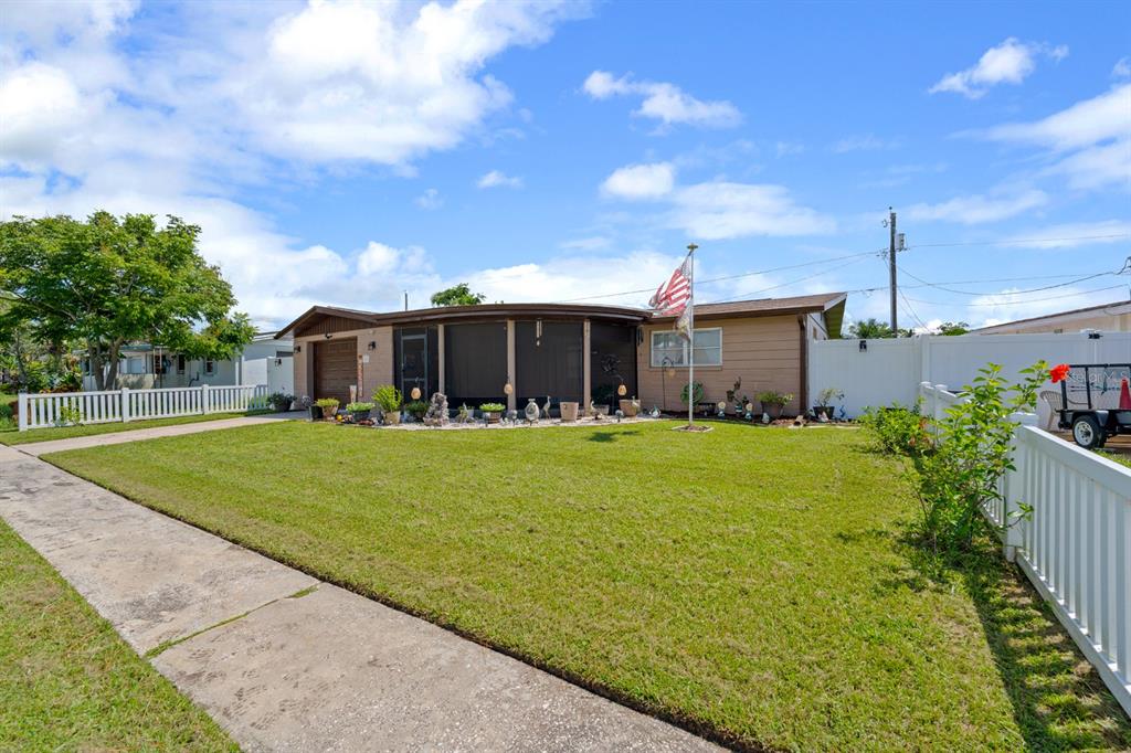 A single-story house with a tan exterior, a screened-in porch, and a white picket fence — 2152 ARCADIA ROAD, HOLIDAY, FL