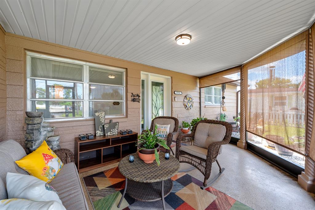 A covered patio features wicker furniture, a patterned rug, and a light-colored ceiling — 2152 ARCADIA ROAD, HOLIDAY, FL