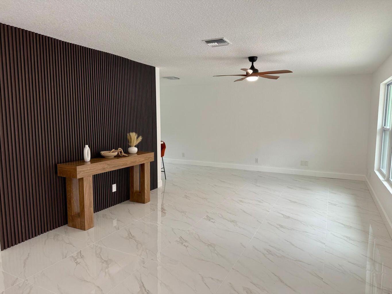 A room with white marble-look tile floors, a dark wood slat accent wall, and console table — 2812 F Road, FL 33470, FL