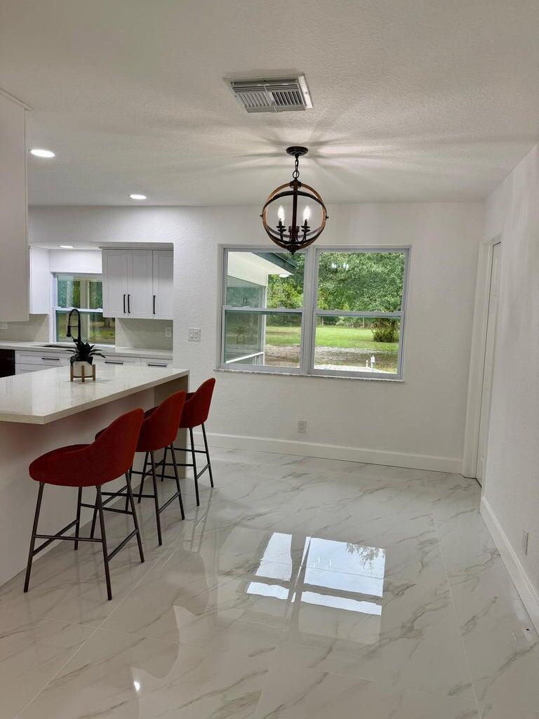 A kitchen with a white island, red bar stools, and a globe pendant light — 2812 F Road, FL 33470, FL