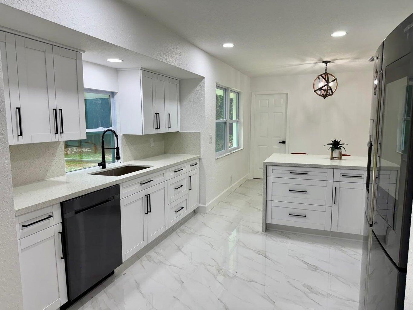 A modern white kitchen features marble-look tile floors, quartz countertops, and a black dishwasher — 2812 F Road, FL 33470, FL