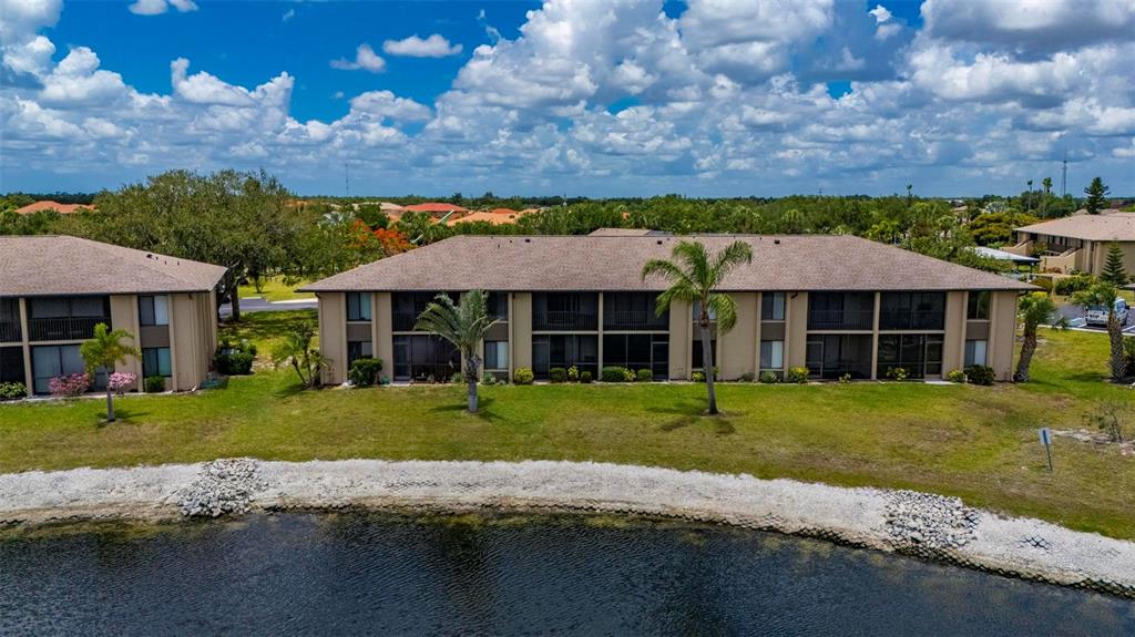 An aerial view of a two-story apartment building situated along a small lake — 4064 OAKVIEW DRIVE UNIT D9, PORT CHARLOTTE, FL