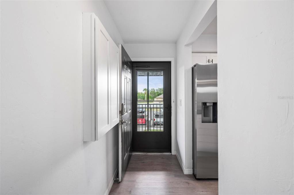 A narrow entryway features a dark front door, white cabinets, and a stainless steel refrigerator — 4064 OAKVIEW DRIVE UNIT D9, PORT CHARLOTTE, FL