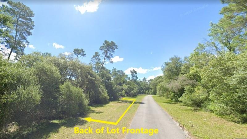 A paved road runs through a wooded lot with yellow arrows indicating the property frontage — 0 SW 32ND COURT, OCALA, FL