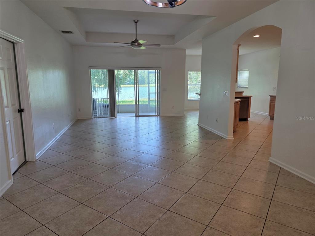 An open-concept living area features tile flooring, a tray ceiling, and sliding glass patio doors — 518 FERN LAKE DRIVE, ORLANDO, FL