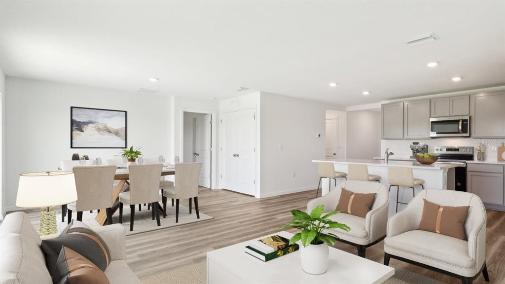 This open-concept living area features a dining space, kitchen with island, and neutral decor — 35461 BRICK CHURCH LOOP, DADE CITY, FL