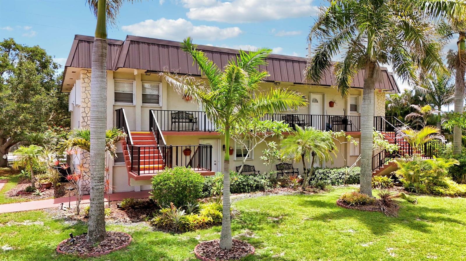 A two-story apartment building with a brown metal roof, exterior staircases, and palm trees — 400 Fern Street # 1c, Jupiter FL 33458, JUPITER, FL