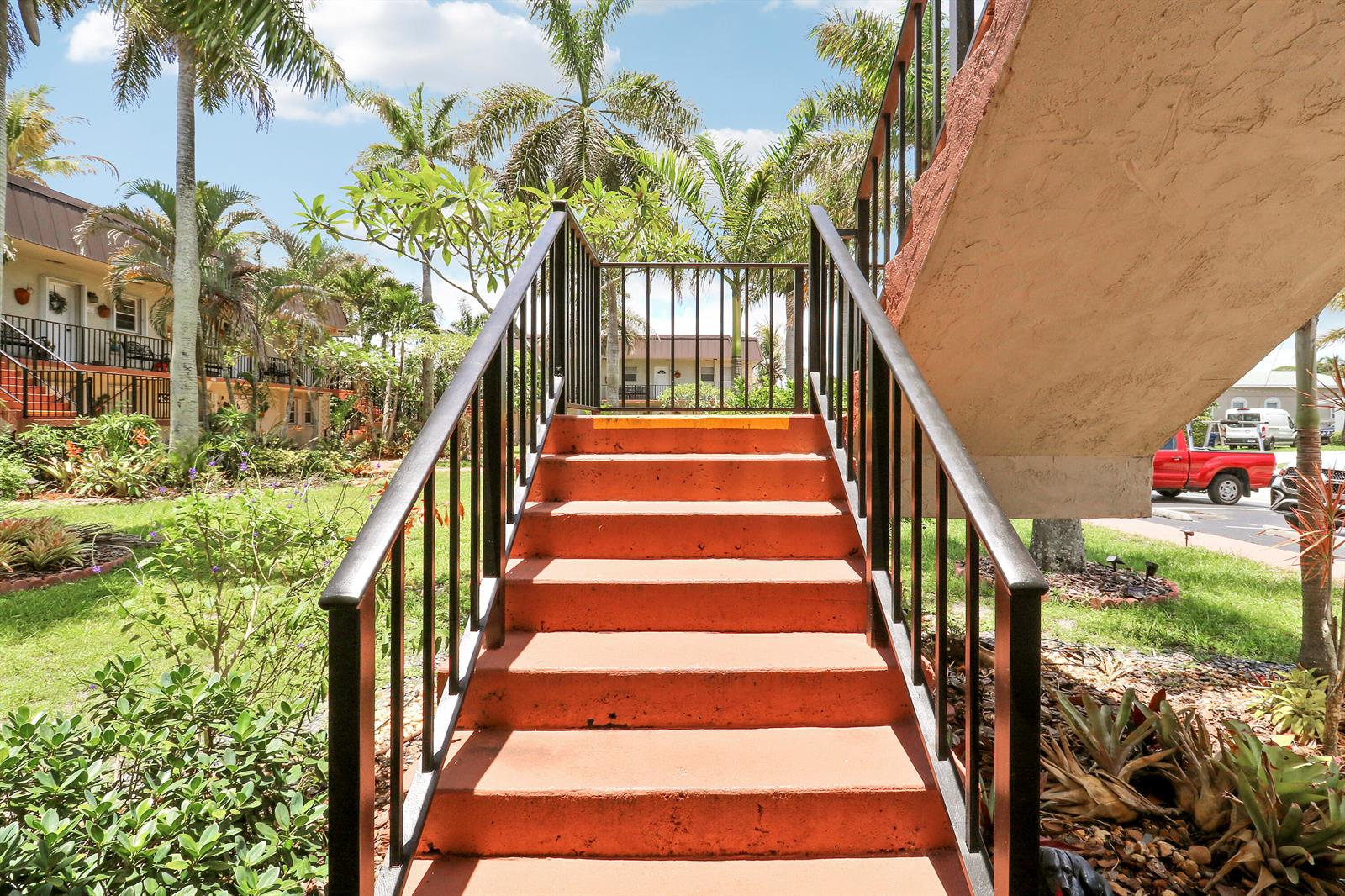 An outdoor concrete staircase with black metal railings leads up to a second-story walkway — 400 Fern Street # 1c, Jupiter FL 33458, JUPITER, FL