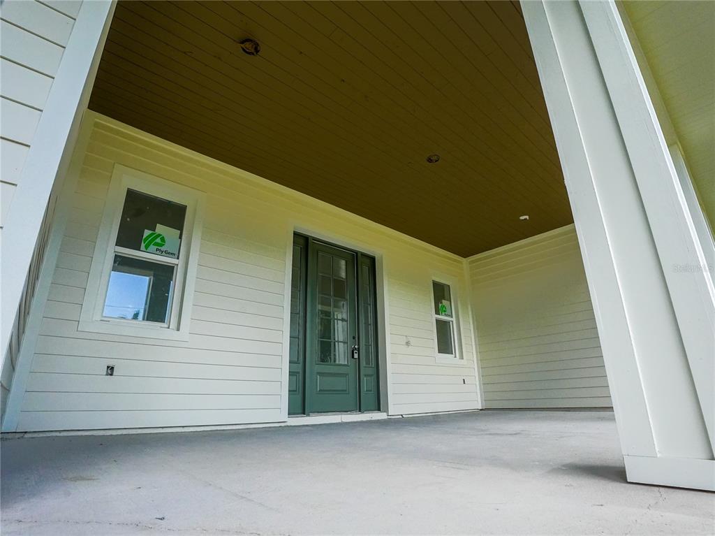 A covered front porch features white horizontal siding, a green front door, and recessed lighting — 1122 DINGENS AVENUE, GOTHA, FL