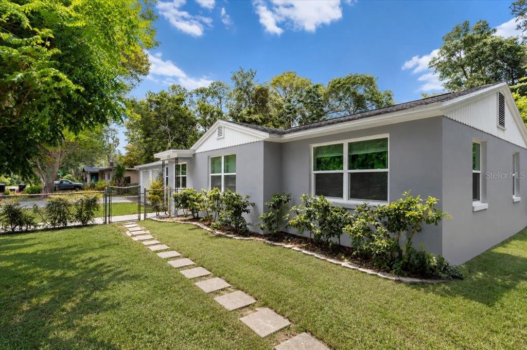 A gray single-story house with a white gable and a stone walkway in the yard — 1116 NW 32ND AVENUE, GAINESVILLE, FL