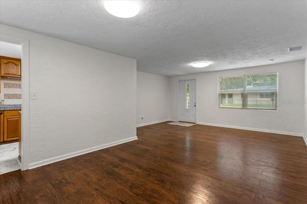 An interior view of a living room with white walls and dark wood-look flooring — 1116 NW 32ND AVENUE, GAINESVILLE, FL