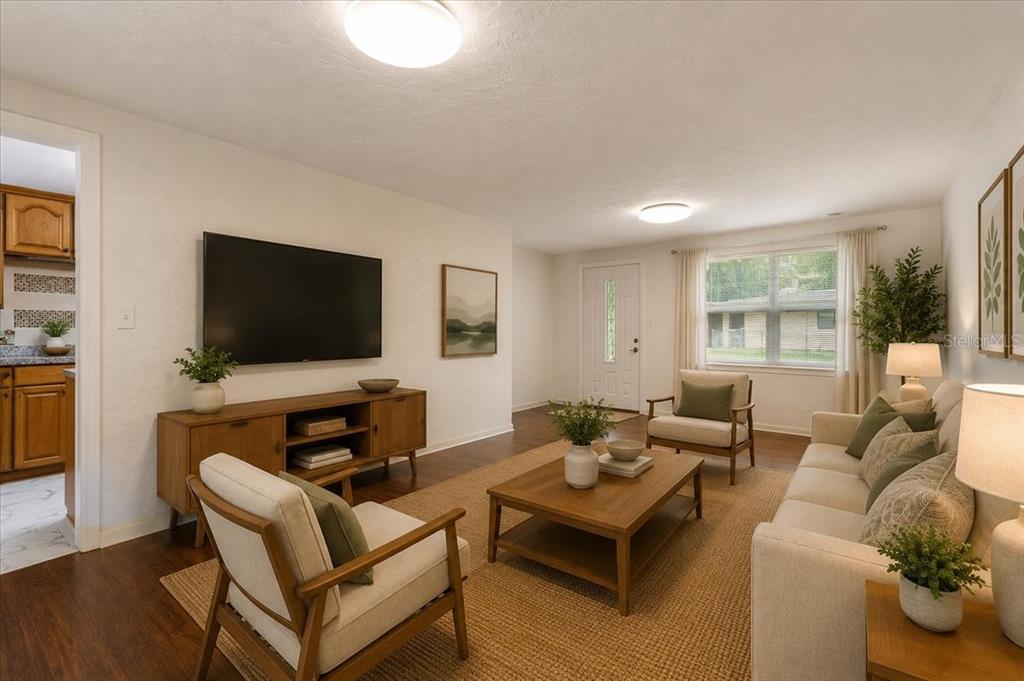 A living room features a television, wooden furniture, a sofa, and armchairs on a rug — 1116 NW 32ND AVENUE, GAINESVILLE, FL
