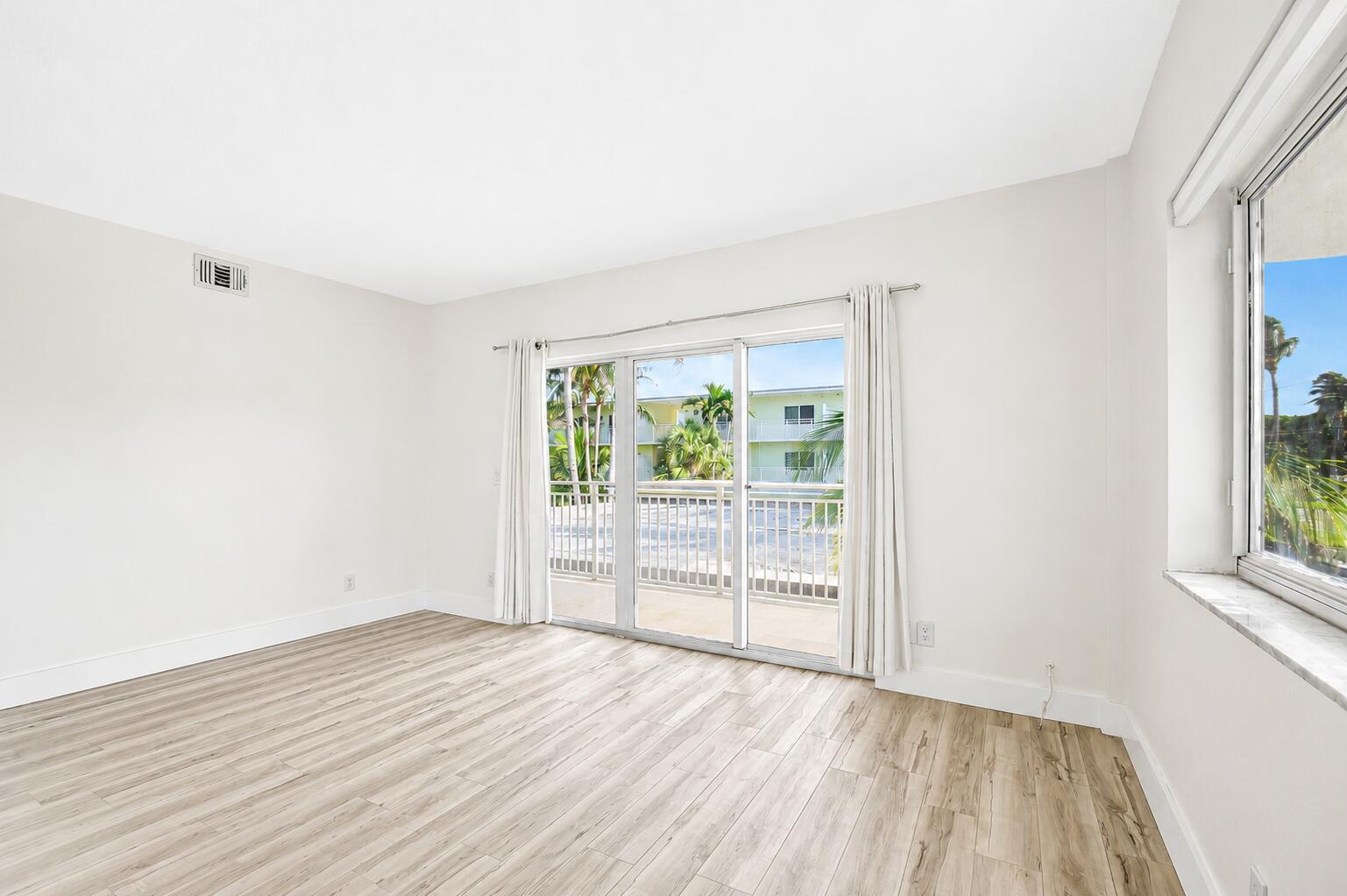 An empty room with light wood-look flooring, white walls, and a sliding glass door balcony — 6520 N Ocean Boulevard # 30, Ocean Ridge FL 33435, OCEAN RIDGE, FL