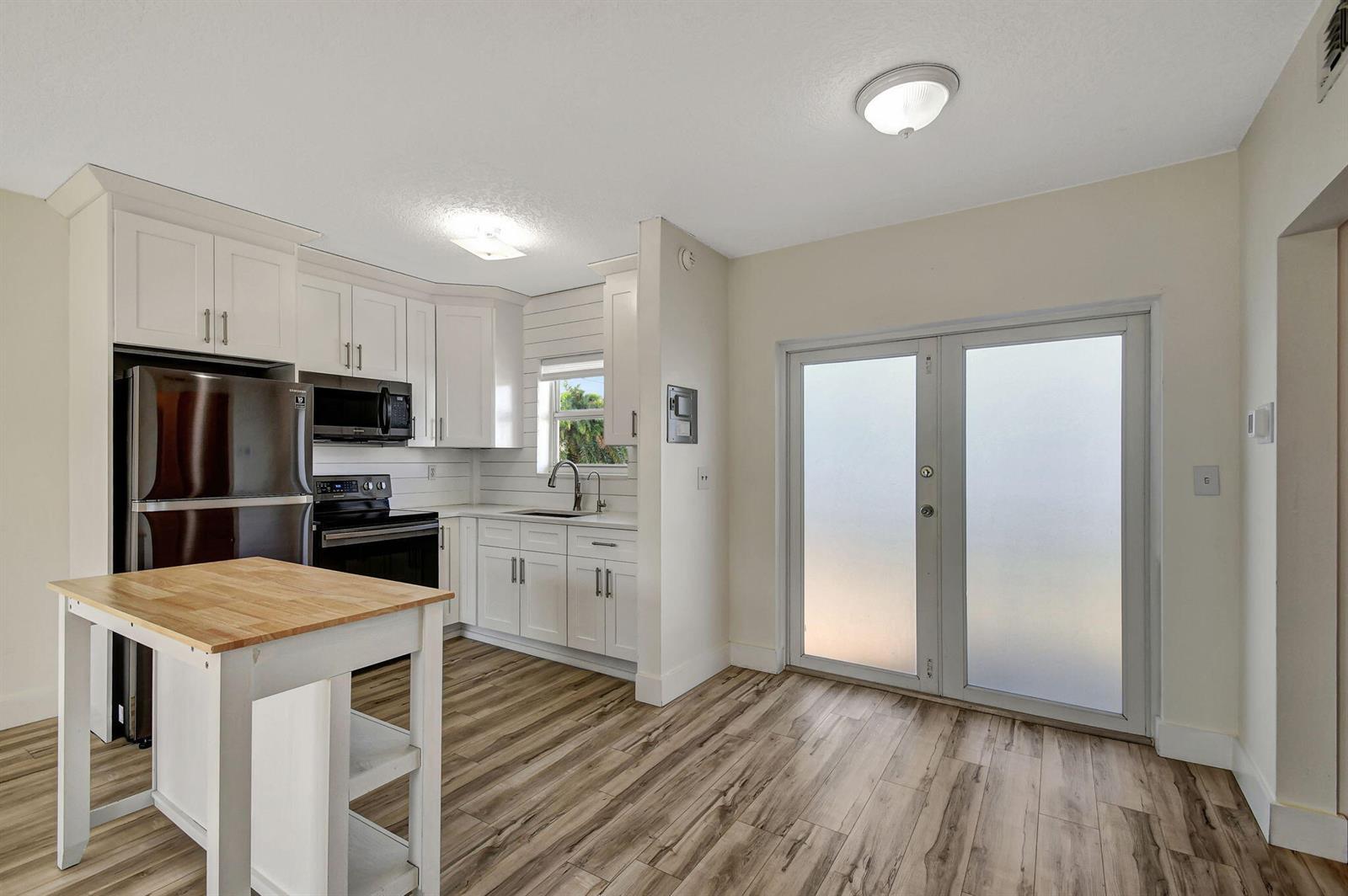 A kitchen with white cabinets, stainless steel appliances, a wooden island, and wood-look flooring — 6520 N Ocean Boulevard # 30, Ocean Ridge FL 33435, OCEAN RIDGE, FL