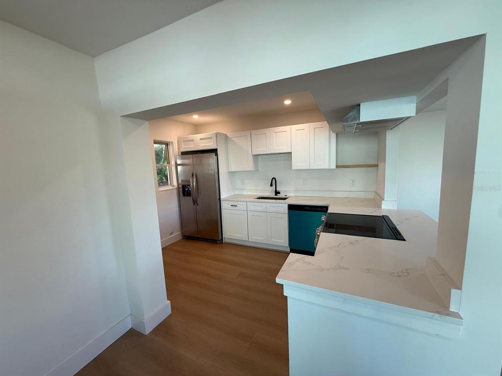 A kitchen features white cabinets, stainless steel appliances, and a white quartz countertop peninsula — 18015 2ND STREET E, REDINGTON SHORES, FL
