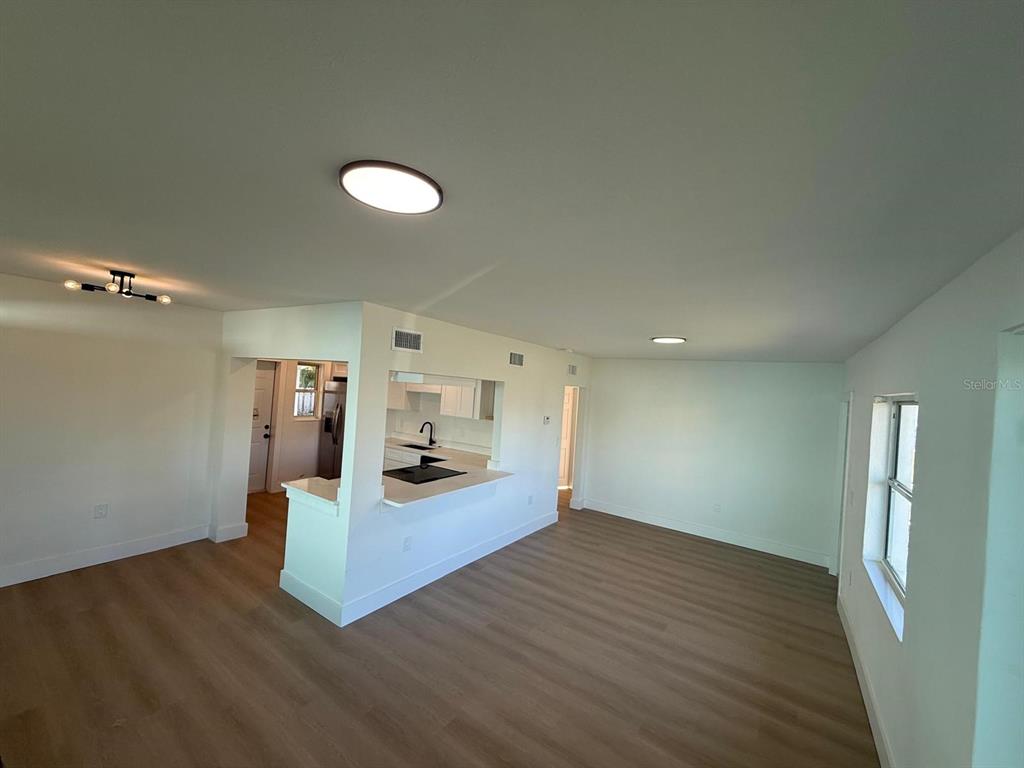 An open-concept living area features light wood-look flooring and a kitchen with a breakfast bar — 18015 2ND STREET E, REDINGTON SHORES, FL
