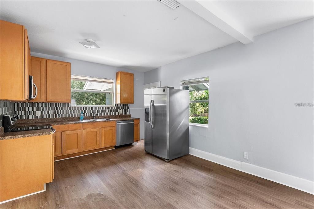 A kitchen features wood cabinets, stainless steel appliances, a tiled backsplash, and wood-look flooring — 811 W AMELIA AVENUE, TAMPA, FL