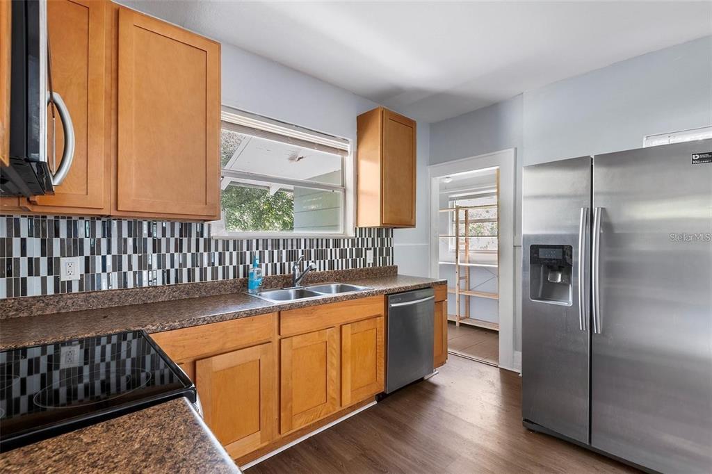 A kitchen with wood cabinets, stainless steel appliances, a tiled backsplash, and wood-look flooring — 811 W AMELIA AVENUE, TAMPA, FL