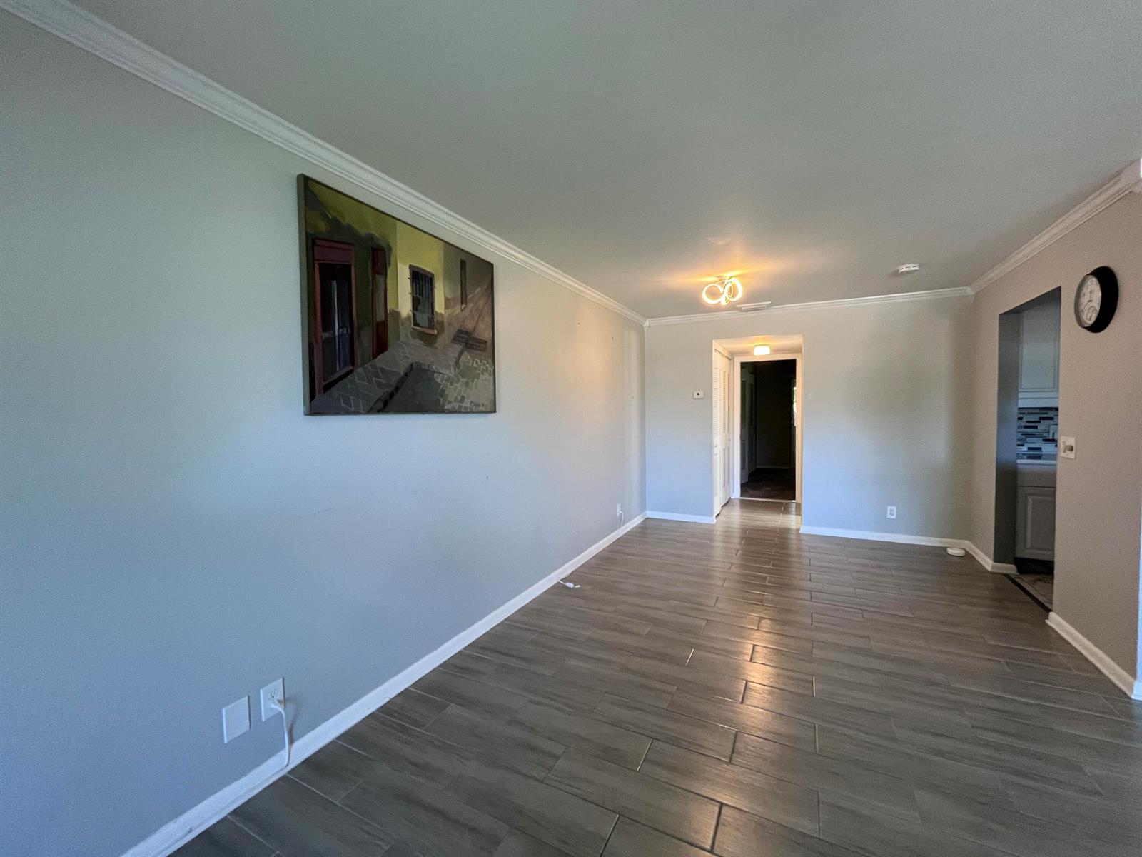 An empty room with gray walls, wood-look tile flooring, crown molding, and a wall painting — 49 Cambridge B, West Palm Beach FL 33417, WEST PALM BEACH, FL