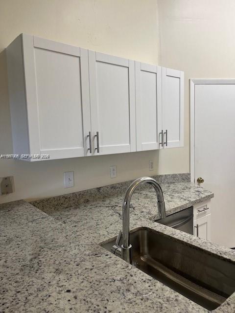 A kitchen features white shaker cabinets, speckled granite countertops, and a stainless steel sink — 9999 Summerbreeze Dr # 918, Sunrise FL 33322, SUNRISE, FL