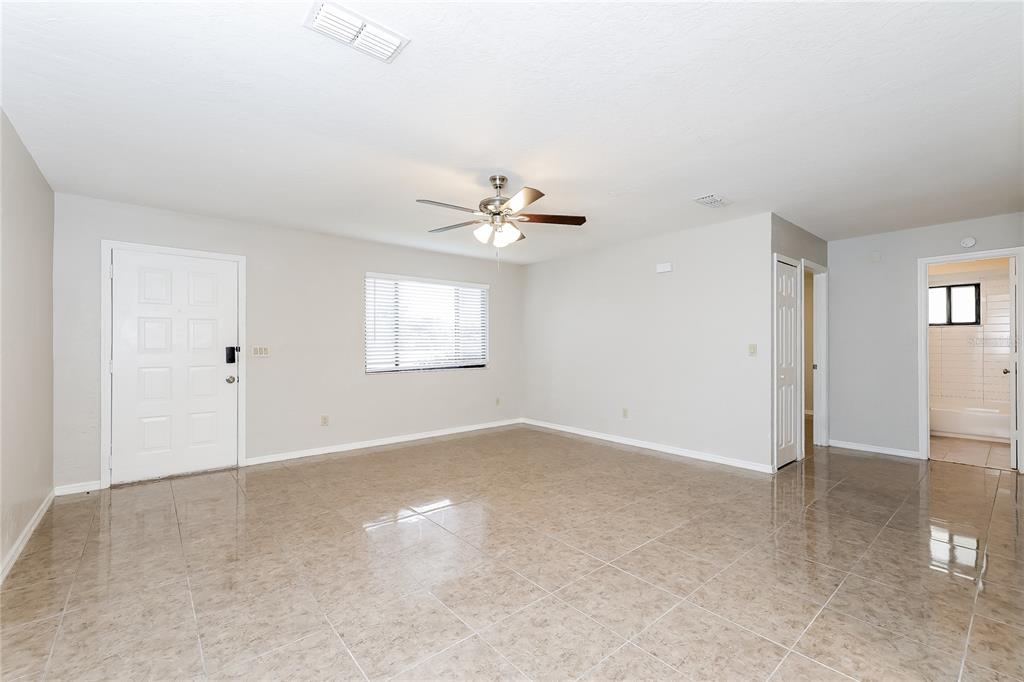 An empty room with light-colored walls, a ceiling fan, and beige tiled flooring — 240 GRIFFORD DRIVE, KISSIMMEE, FL