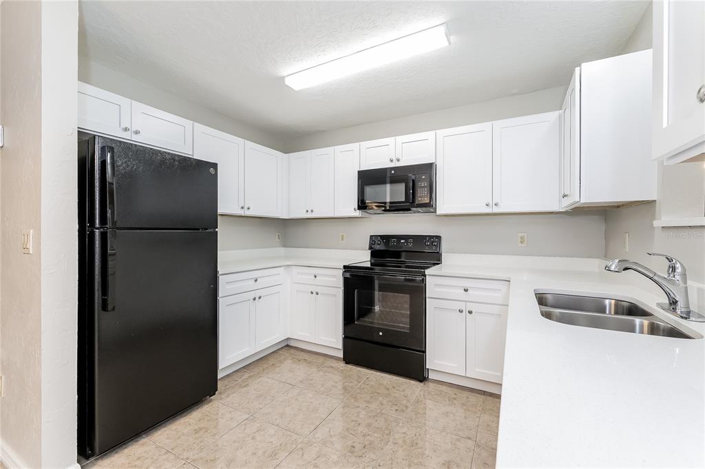 A kitchen with white cabinets, black appliances, and light-colored countertops — 240 GRIFFORD DRIVE, KISSIMMEE, FL