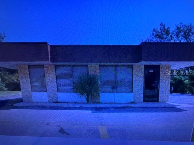 A single-story commercial building features a stone facade, large windows, and a dark overhang — 887 DELTONA BOULEVARD, DELTONA, FL