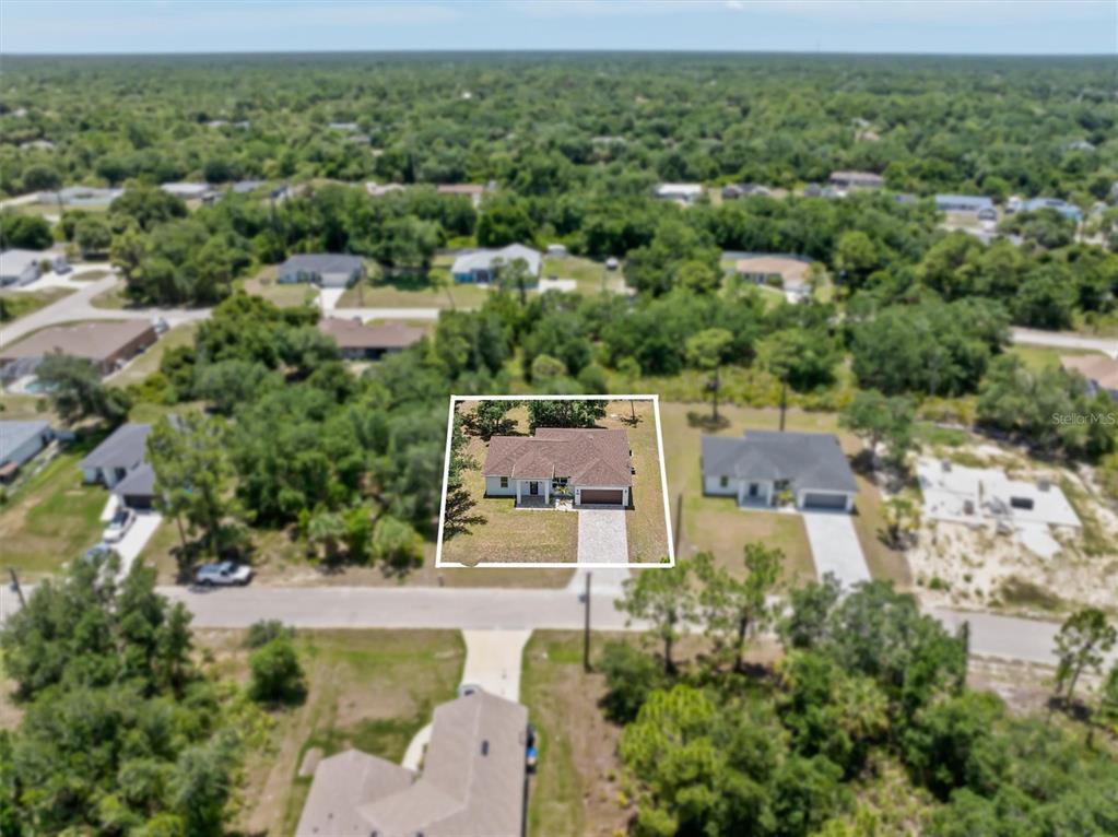 An aerial view shows a single-story house with a brown roof and a paved driveway — 5273 CAPUTO AVENUE, NORTH PORT, FL