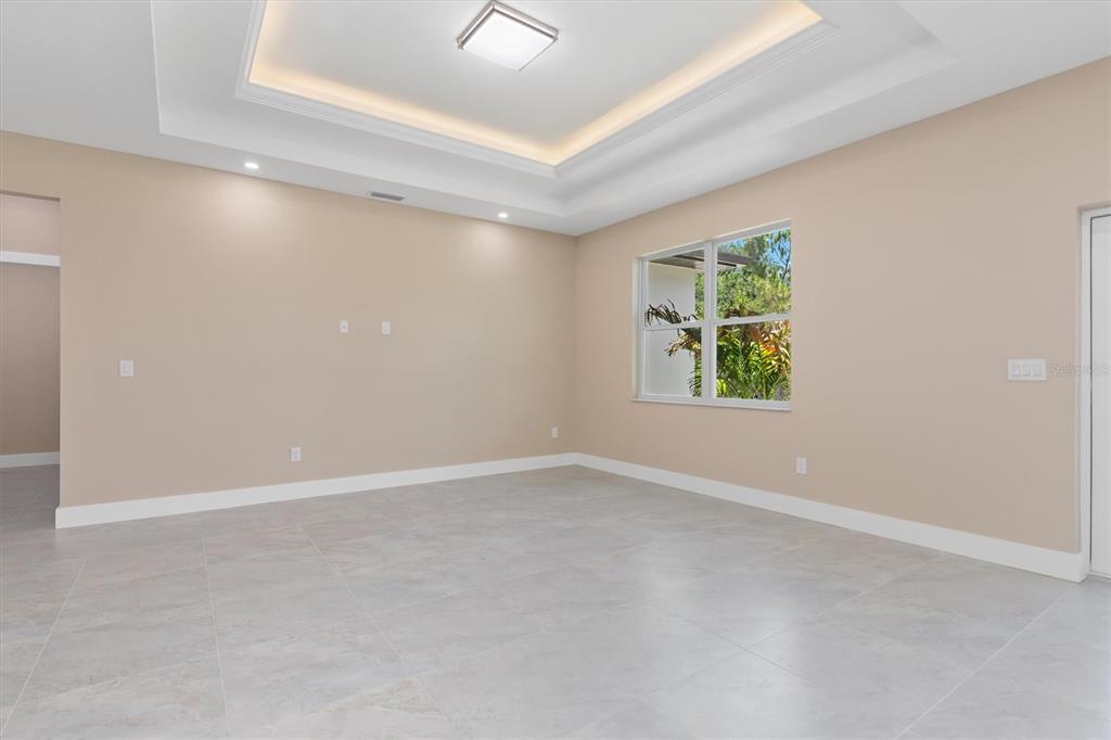 An empty room with beige walls, tile flooring, and a tray ceiling with recessed lighting — 5273 CAPUTO AVENUE, NORTH PORT, FL