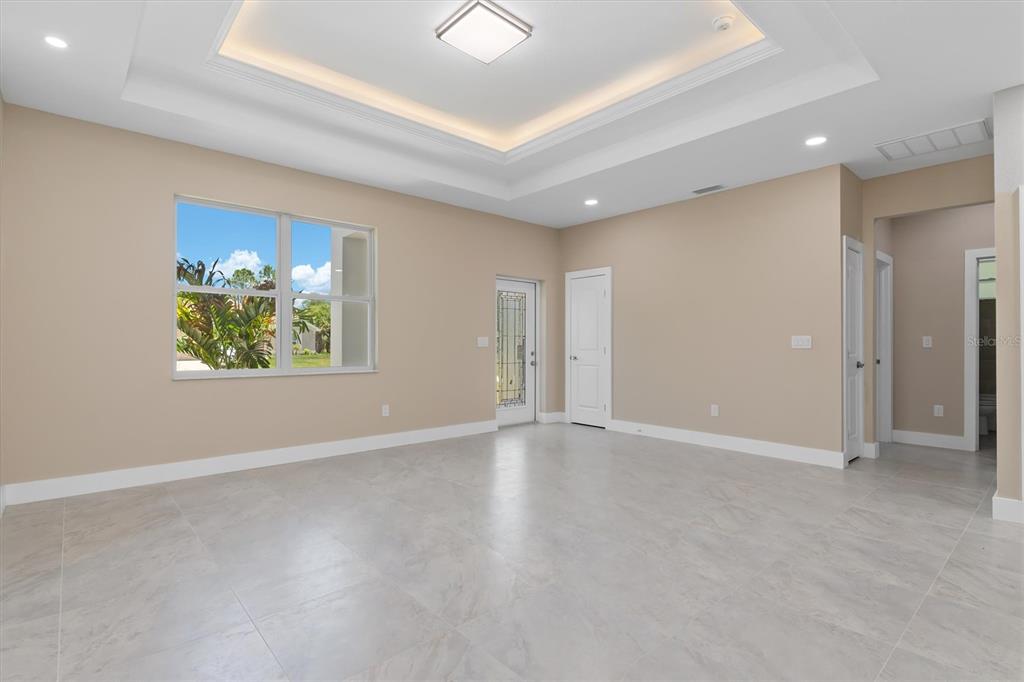 A spacious room with light-colored tile flooring, a tray ceiling, and a glass-paneled door — 5273 CAPUTO AVENUE, NORTH PORT, FL
